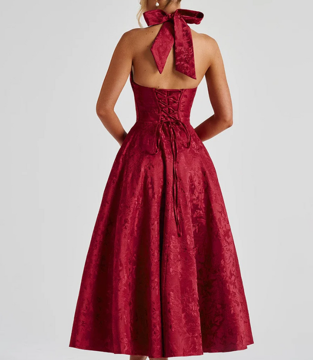 Back view of a red jacquard midi dress, showing the halter bow tie and corset lacing.