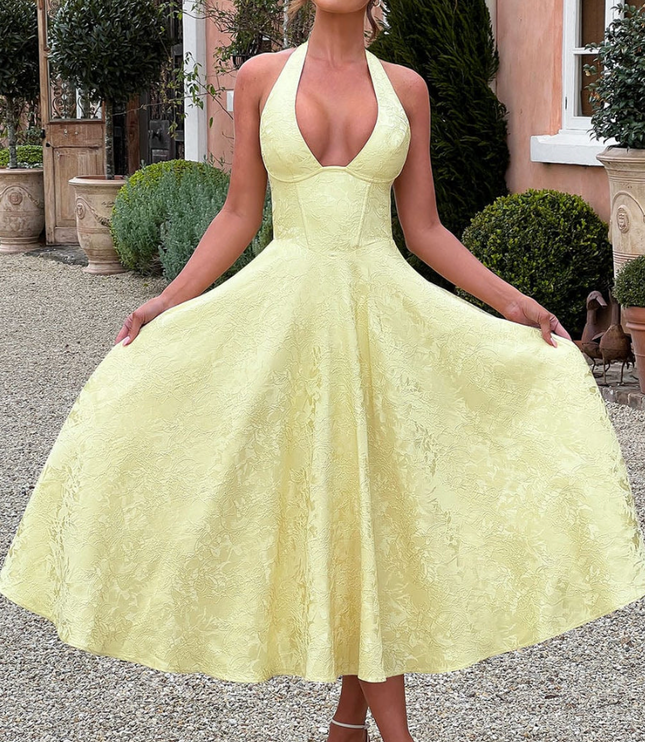 Full-length view of a yellow jacquard halter v-neck midi dress, featuring a textured pattern.