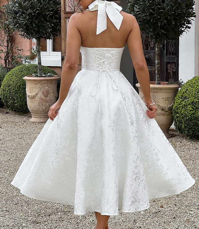 Back view of a white jacquard midi dress with a lace-up corset back and halter tie detail.