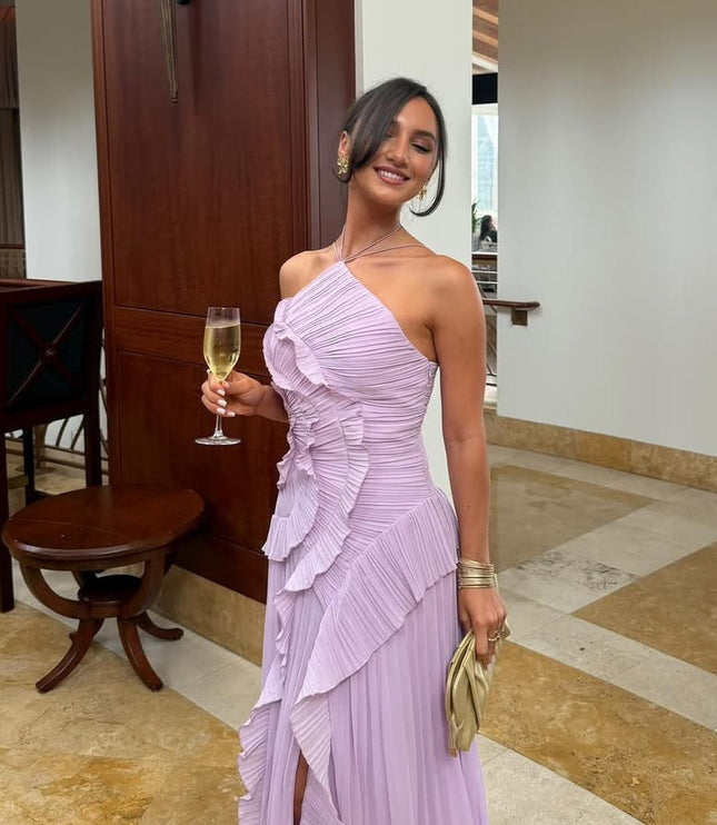 Women's lavender one-shoulder dress with a ruffled bodice and pleated skirt, styled with a champagne flute and gold clutch.