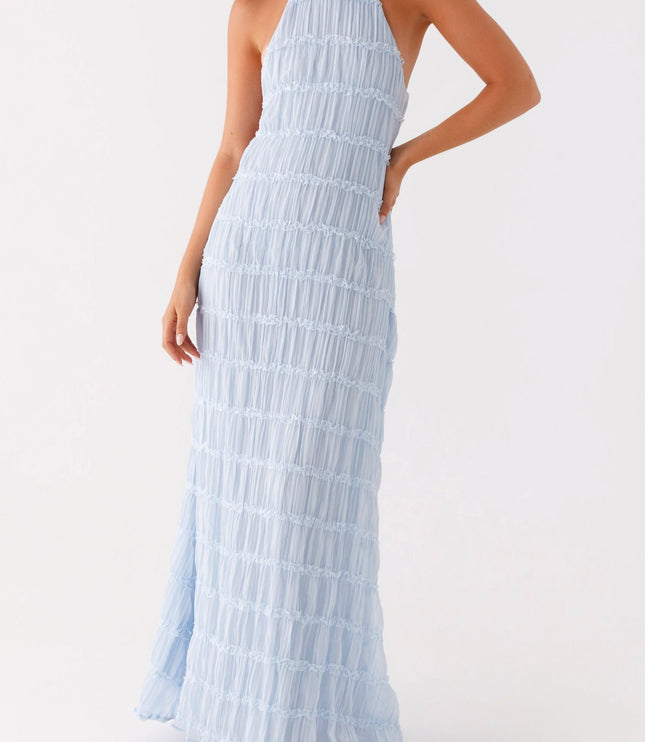 Side view of the light blue open back halter neck maxi dress, showing the flow of the skirt.