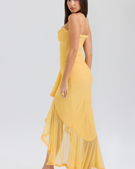 Side view of a yellow women's prom maxi dress, showcasing the sheer ruffled high-low hem and fitted silhouette.