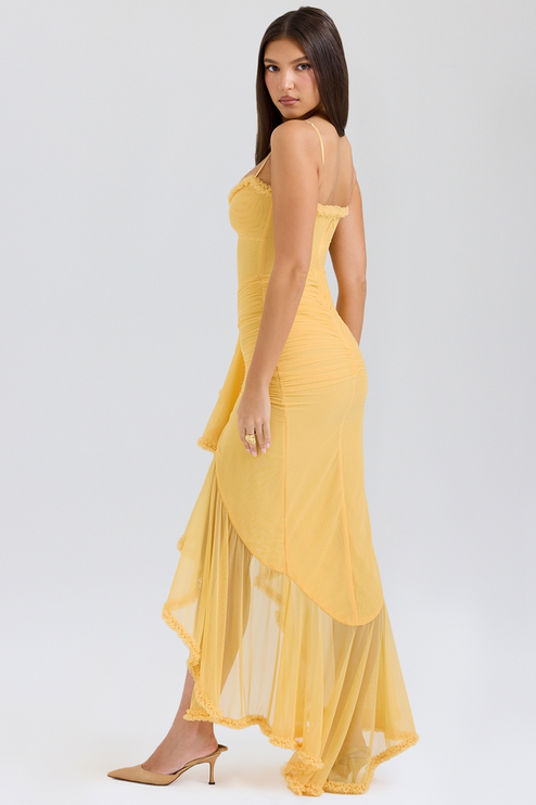 Side view of a yellow women's prom maxi dress, showcasing the sheer ruffled high-low hem and fitted silhouette.