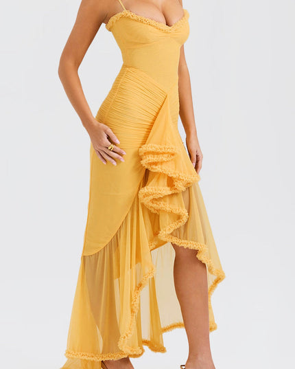 Side profile of a women's yellow prom maxi dress, showing the asymmetrical ruffled skirt and a high slit, paired with gold heels.