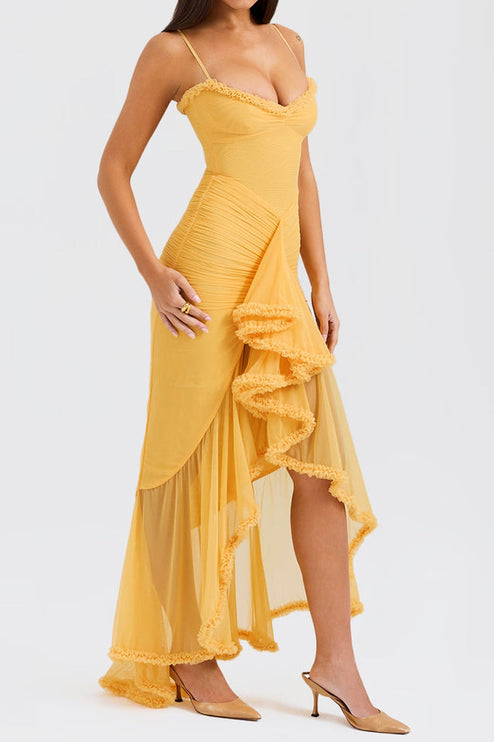Side profile of a women's yellow prom maxi dress, showing the asymmetrical ruffled skirt and a high slit, paired with gold heels.
