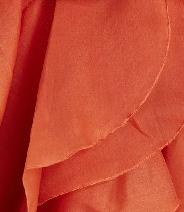 Close-up detail of the coral fabric and layered ruffles of the strapless maxi dress, showing the texture and construction of the flowing tiers.