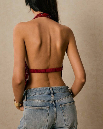 Back view of a women's red sequin halter top, showing the open back design and elastic band, paired with light wash jeans.