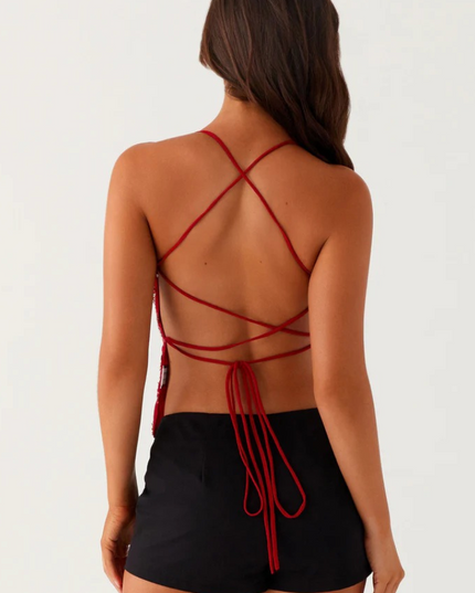 Back view of a red sequin V-neck cami top showing criss-cross strap detailing and tie closure, worn with black shorts.