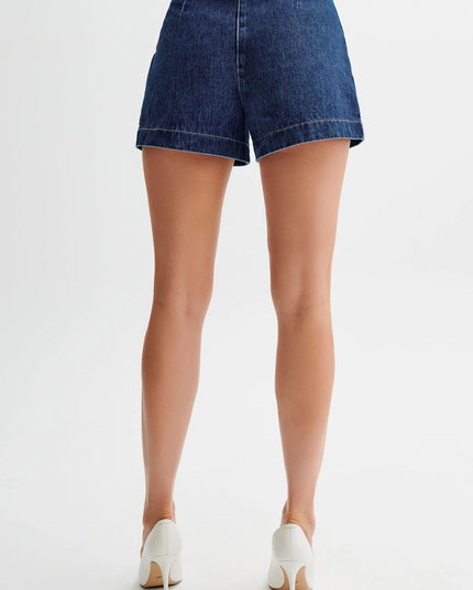 Back view of dark wash denim shorts with a high waist and visible back pockets, paired with white stiletto heels.
