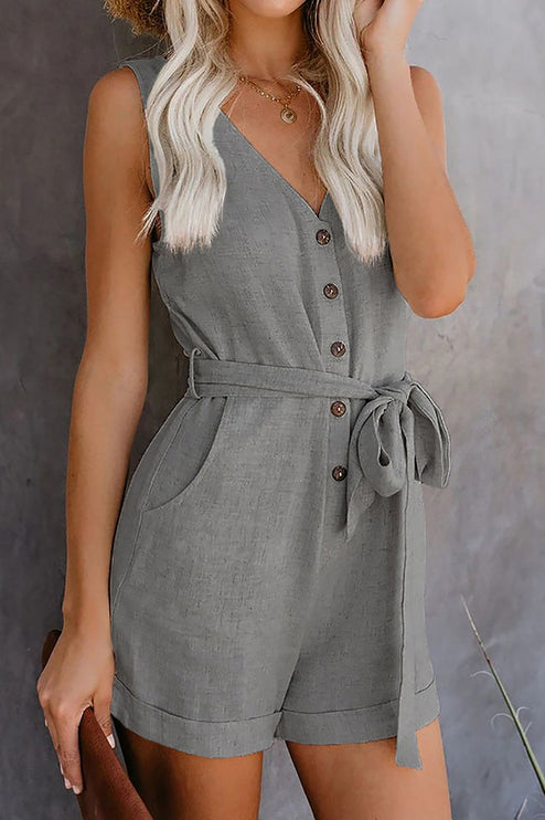 Front view of a women's grey sleeveless V-neck romper, showcasing the tie waist, buttons, and cuffed shorts.