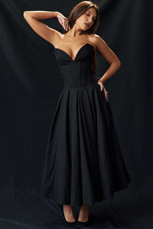 Full length view of black strapless boned bodice midi dress with pleated skirt, woman posing.