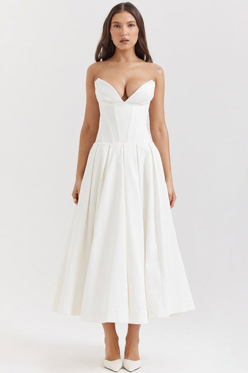 Front view of a white strapless midi dress with a boned bodice and pleated skirt, paired with white heels.