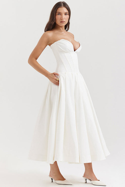 Profile view of a white strapless midi dress, highlighting the structured boned bodice and flowing pleated skirt.