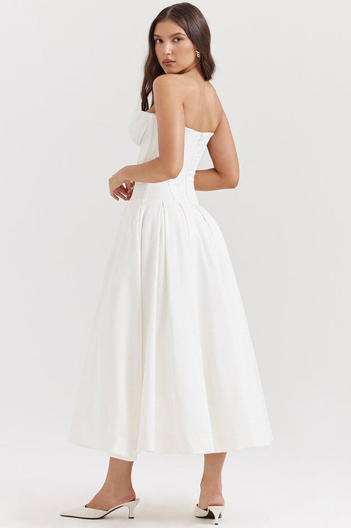 Three-quarter back view of a white strapless midi dress, showcasing the pleated skirt and corset-style top.