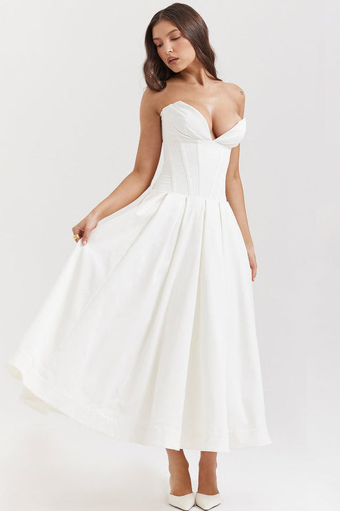 Side view of a white strapless boned bodice midi dress, showing the full pleated skirt and white heels.