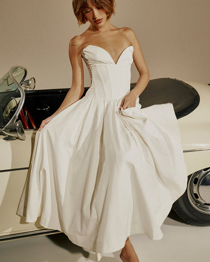 White strapless boned bodice midi dress with pleated skirt, shown with a vintage car, paired with white heels.