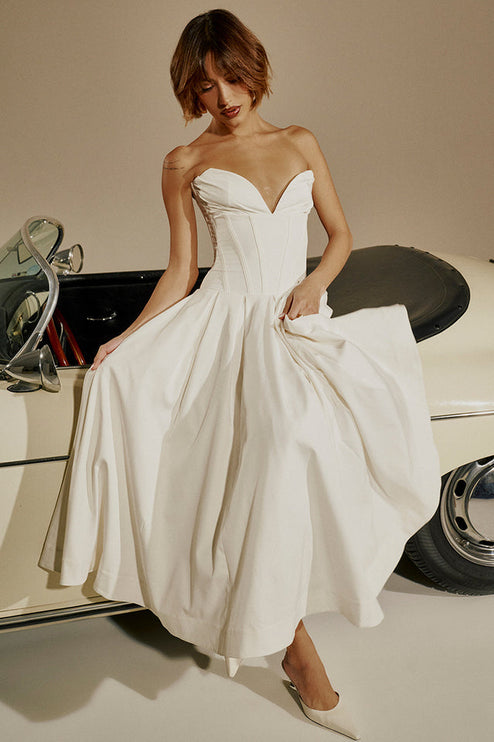 White strapless boned bodice midi dress with pleated skirt, shown with a vintage car, paired with white heels.