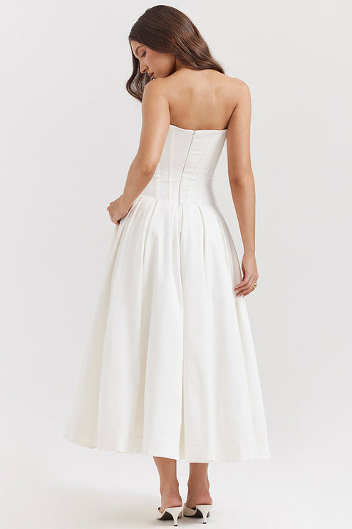 Back view of a white strapless boned bodice pleated midi dress, with a visible zipper closure.