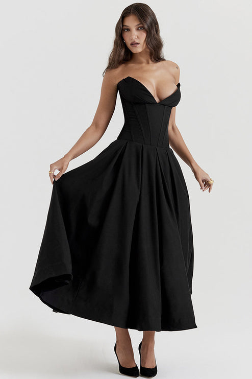 Women's black strapless midi dress with boned bodice and full pleated skirt, hands on skirt.