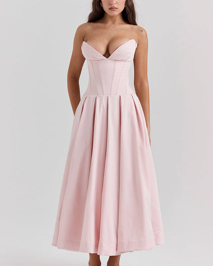 Front view of a pink strapless midi dress with a boned bodice and a full pleated skirt, with white heels.