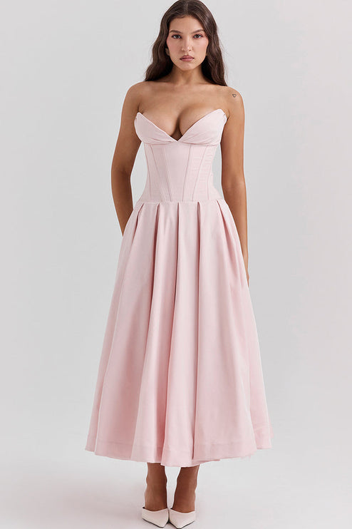 Front view of a pink strapless midi dress with a boned bodice and a full pleated skirt, with white heels.