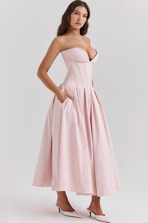 Profile view of a pink strapless midi dress, highlighting the boned bodice, pleated skirt, and functional pockets.