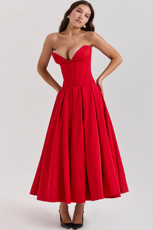 Woman posing with hands on hips in a red strapless boned bodice pleated midi dress, showcasing the full skirt.