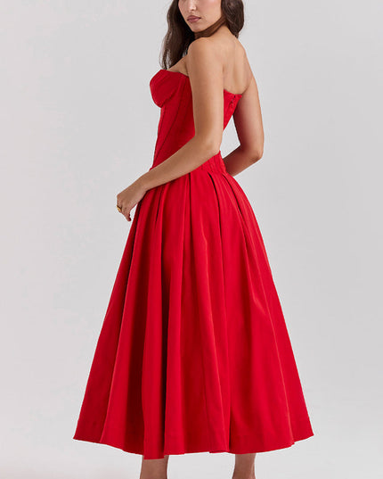 Side view of a woman wearing a red strapless boned bodice pleated midi dress, showing the elegant silhouette.