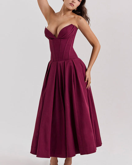 Woman with arm raised, showcasing the movement of a burgundy strapless boned bodice pleated midi dress.