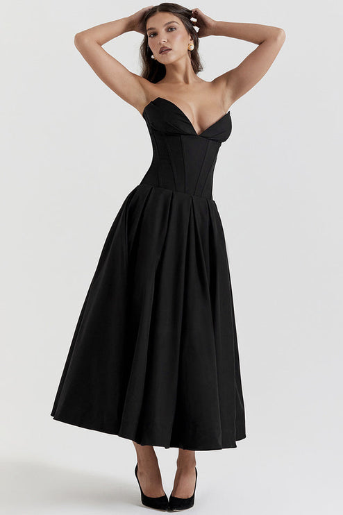 Elegant black strapless boned bodice midi dress, pleated skirt, woman posing with hands above head.