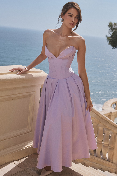 Lavender strapless boned bodice pleated midi dress for women, shown outdoors with ocean background