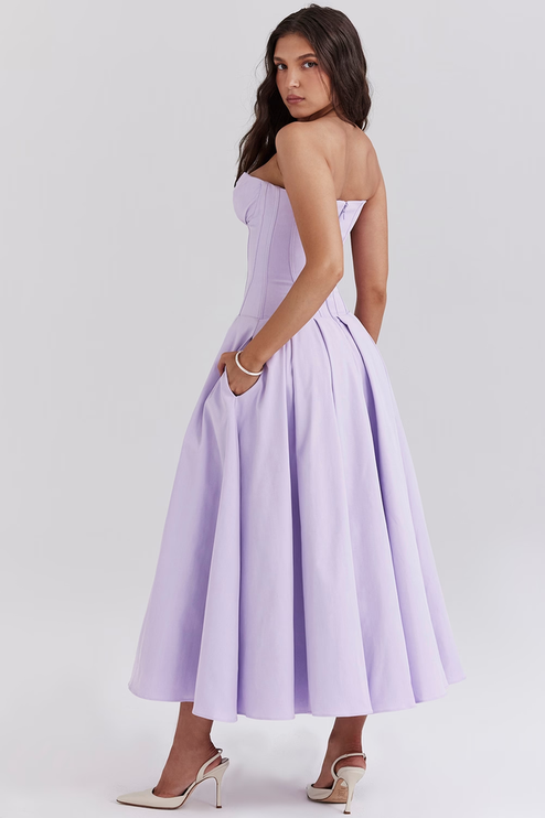 Three-quarter back view of women's lavender strapless boned bodice pleated midi dress with pockets