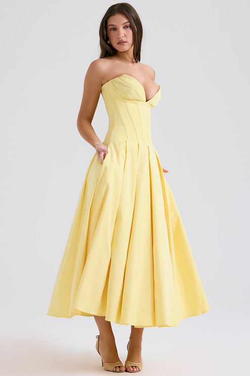 Angled view of a women's light yellow strapless boned bodice pleated midi dress, with pockets
