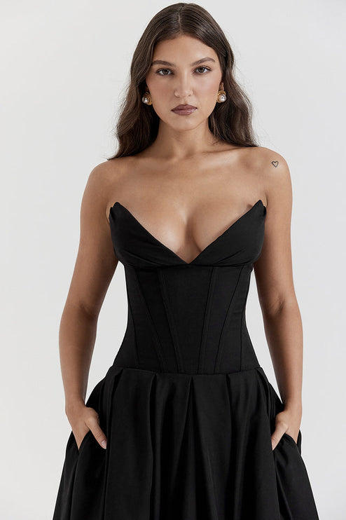 Close up of black strapless boned bodice midi dress, sweetheart neckline and pleated skirt with pockets.
