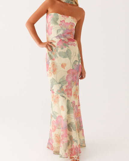 Full length front view of women's strapless floral maxi dress with an asymmetrical hem, styled with white heels.