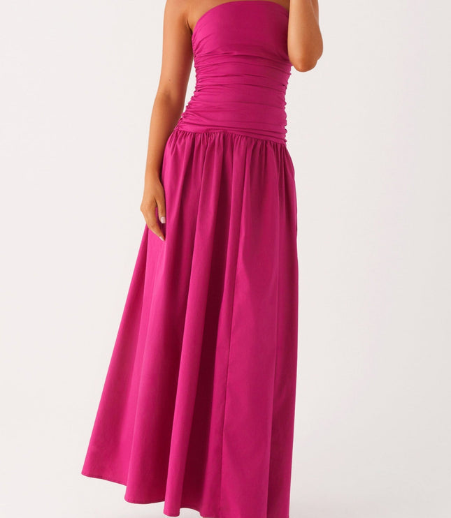 Women's fuchsia strapless ruched maxi dress in a dynamic pose, showing the full skirt and drop waist design.