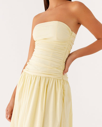 Close-up of the ruched bodice and gathered drop waist of the pale yellow strapless maxi dress.