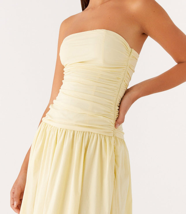 Close-up of the ruched bodice and gathered drop waist of the pale yellow strapless maxi dress.