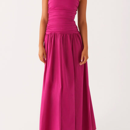 Front view of a women's strapless ruched fuchsia maxi dress with a drop waist, paired with white heels.