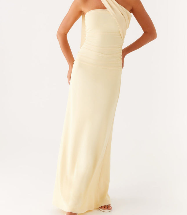 Full-length view of a women's strapless ruched neck scarf maxi dress in pale yellow, with hands on hips.