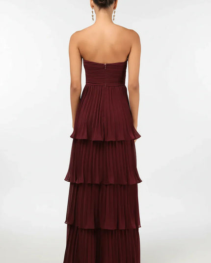Back view of the women's burgundy strapless tiered pleated maxi dress, showing the full skirt and zipper detail.