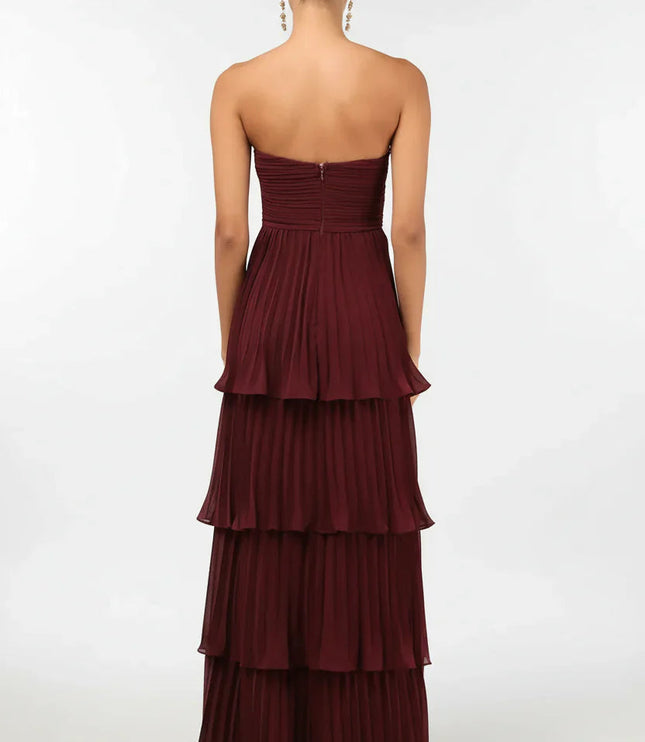 Back view of the women's burgundy strapless tiered pleated maxi dress, showing the full skirt and zipper detail.