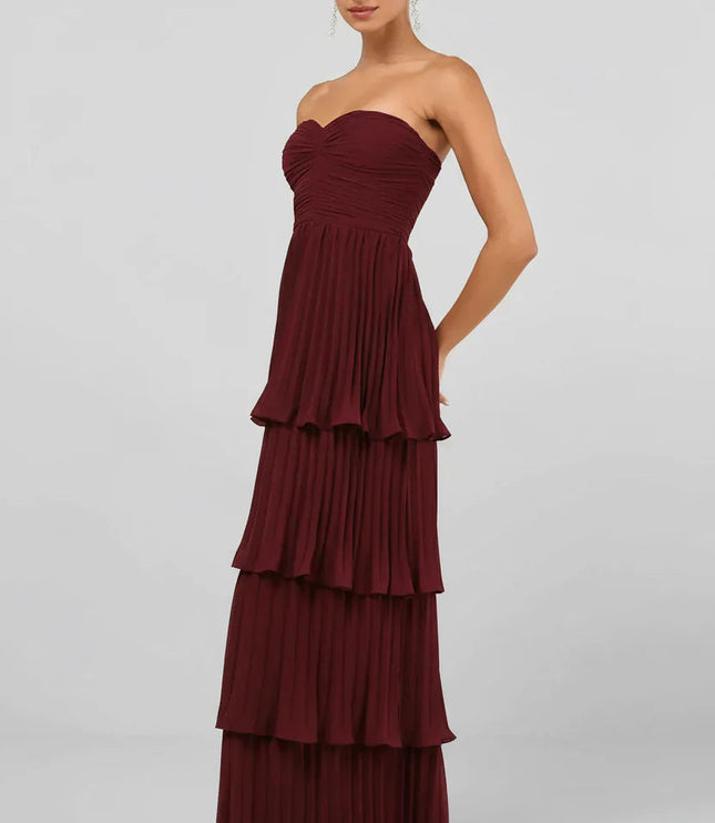 Side profile of the women's strapless tiered pleated maxi dress in burgundy, highlighting the flowing pleats.