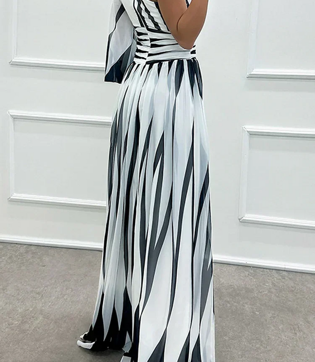Side view of black and white striped one-shoulder maxi dress, showing the flowing skirt and single sleeve