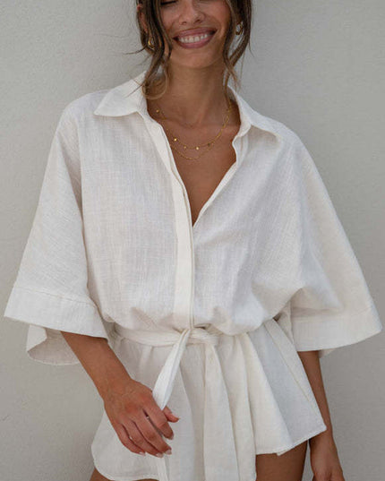 Close-up of a women's summer collared button-front short romper in textured white fabric with a tied waist.