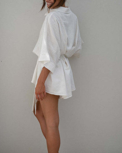 Three-quarter back view of a women's white summer collared short romper, highlighting the loose sleeves and waist tie.