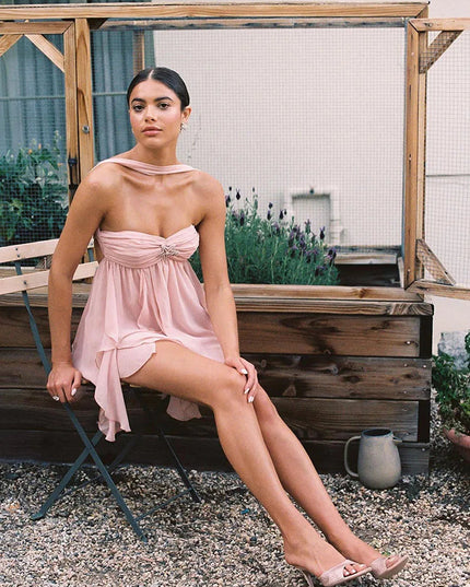 Pink ruffle mini dress with a halter neck and strapless bodice, showcasing the layered skirt and designer shoes.