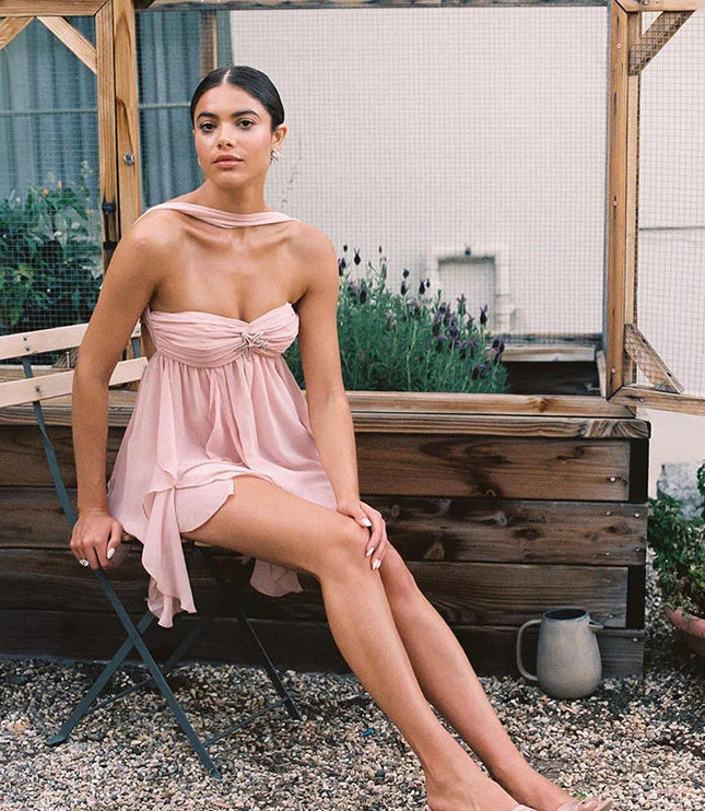 Pink ruffle mini dress with a halter neck and strapless bodice, showcasing the layered skirt and designer shoes.