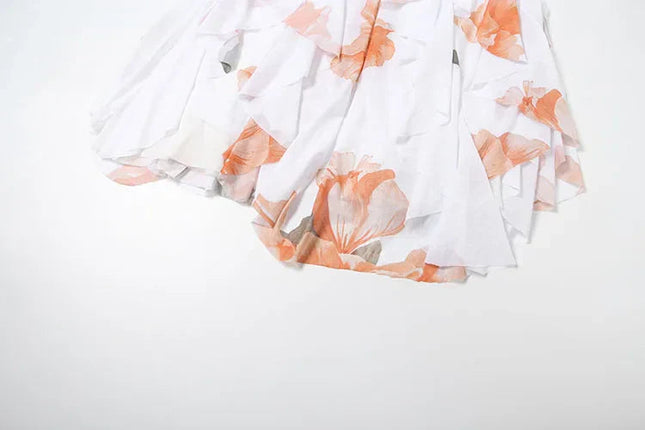 Detail of the white summer floral ruffle mini dress with orange floral print and cascading ruffles on the skirt.