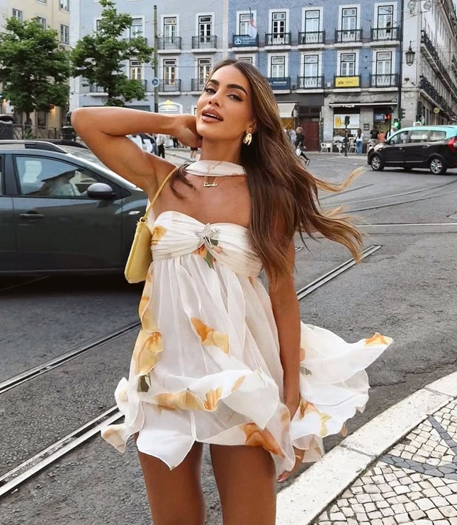 Flowy white summer floral ruffle mini dress with orange details, showcasing the movement of the skirt and halter neck.